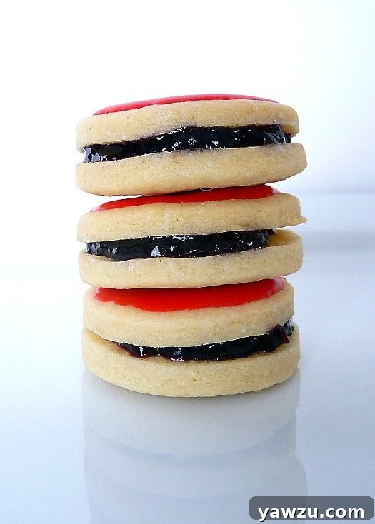 A close-up of a stack of three Empire cookies, showcasing their intricate details and festive icing.
