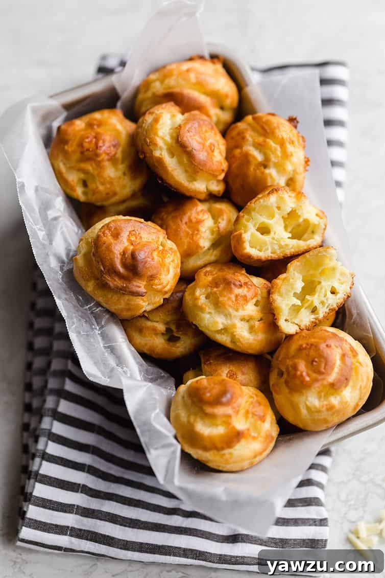 A charming wicker basket overflowing with golden-brown Gougères, with one split open revealing its airy interior.
