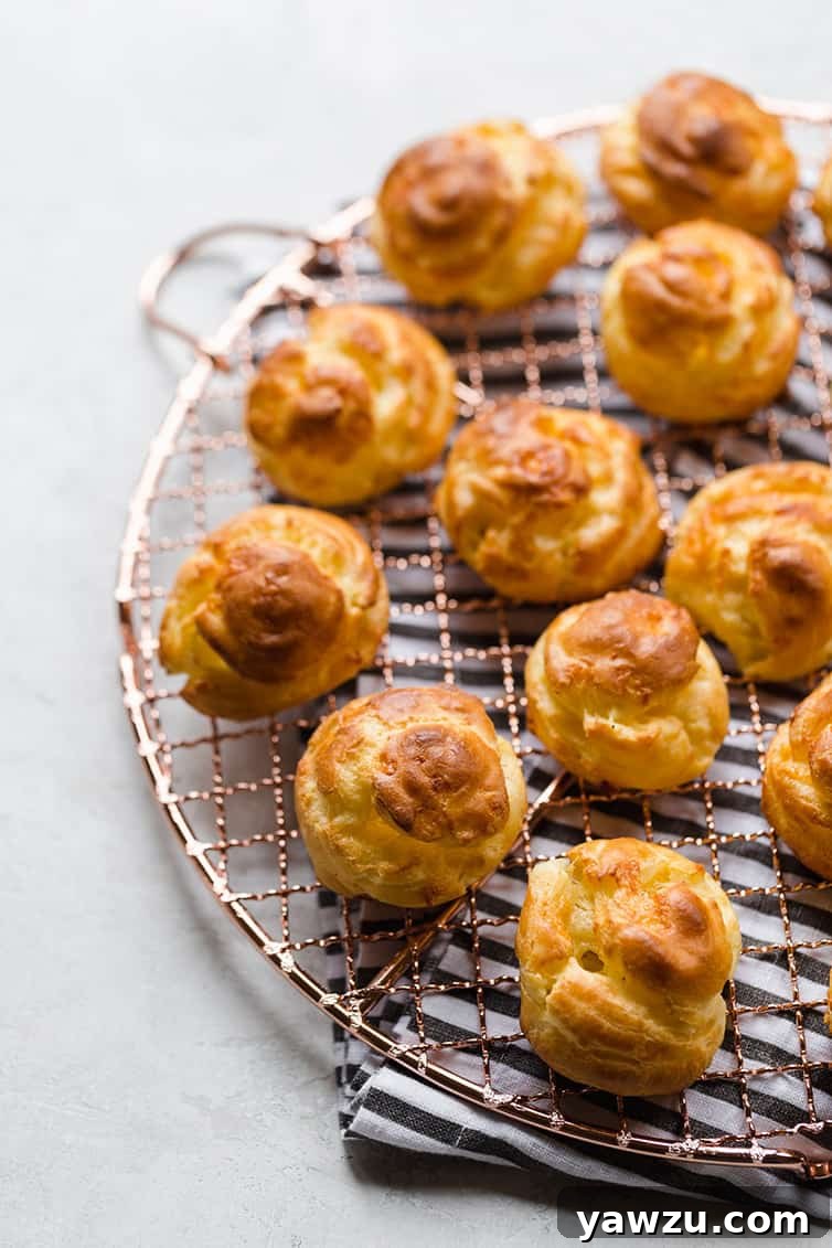 Freshly baked Gougères cooling on a wire rack, showcasing their puffed, golden exterior.