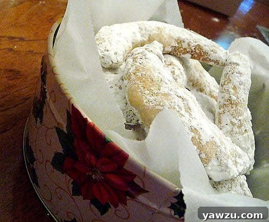 A festive cookie tin filled with dozens of powdered sugar-dusted Nut Crescent Cookies, perfect for gifting.