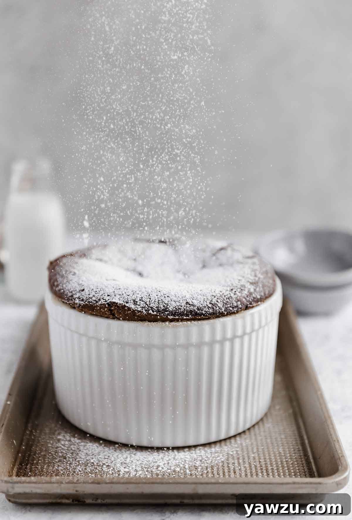 Photo of chocolate souffle being sprinkled with a large dusting of powdered sugar.