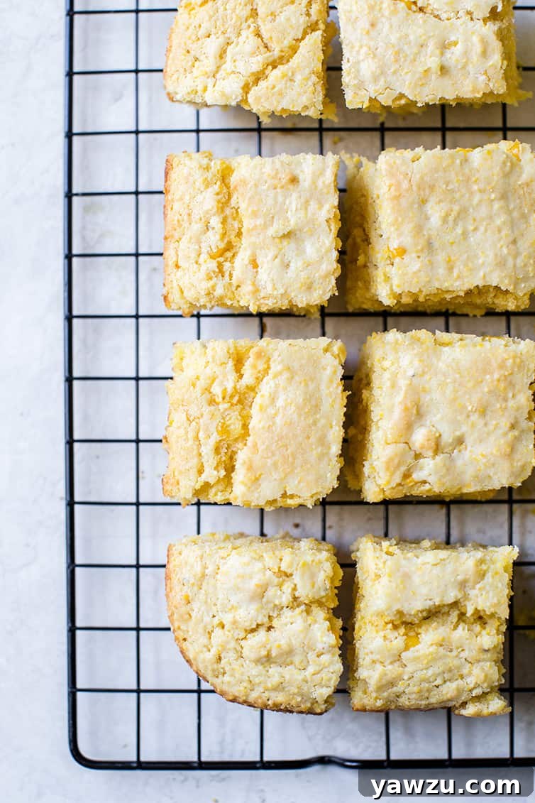 Freshly baked squares of cornbread cooling on a wire rack, steam gently rising.