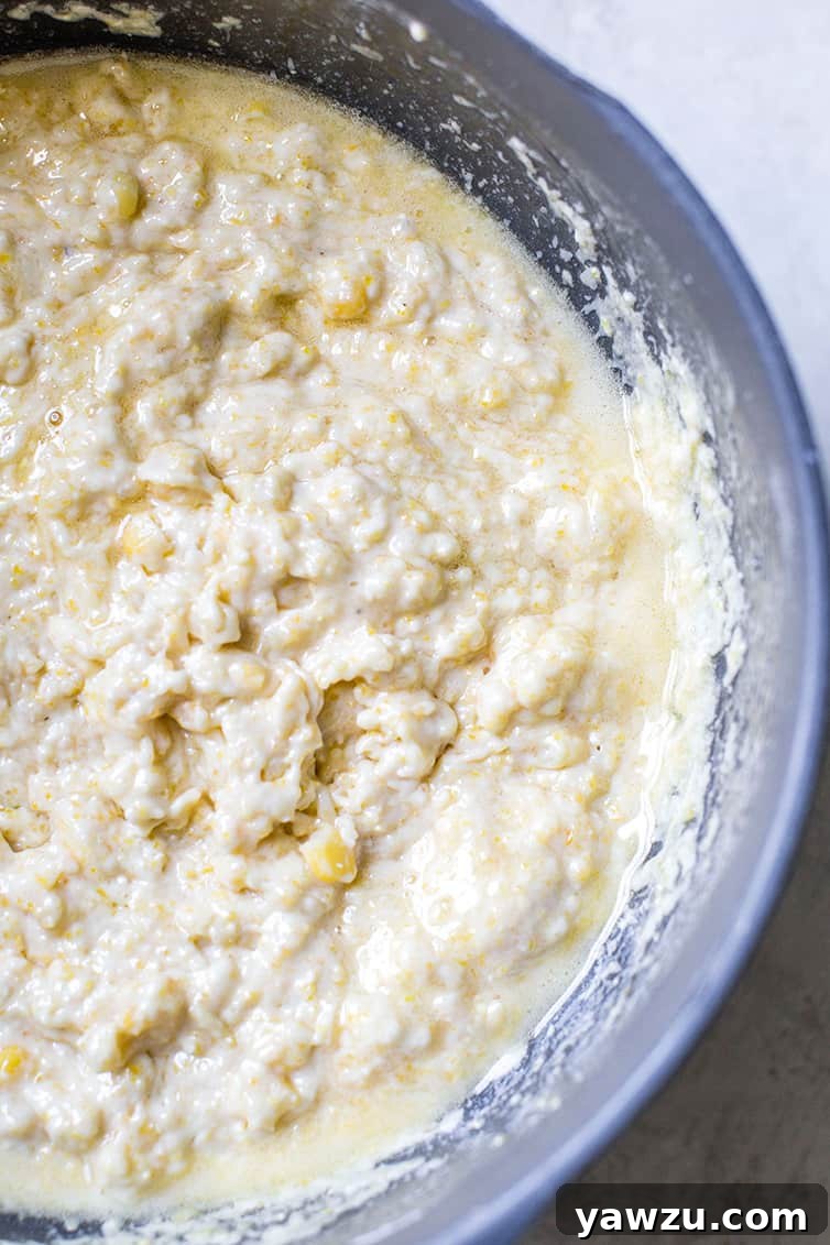 A bowl of cornbread batter with a rich, creamy consistency and visible corn kernels.