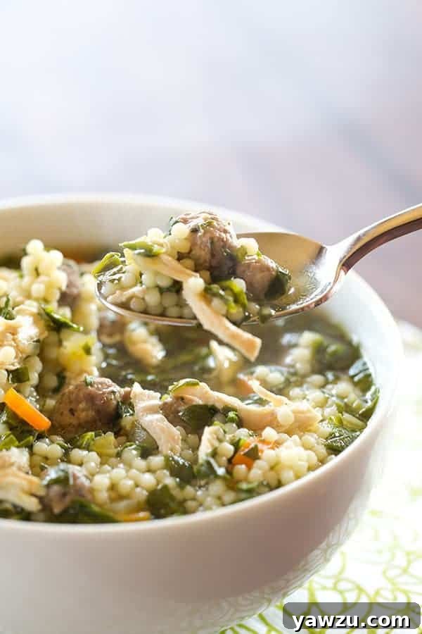 A comforting bowl of classic Italian wedding soup, filled with miniature pasta, tender shredded chicken, fresh spinach, and savory little meatballs.