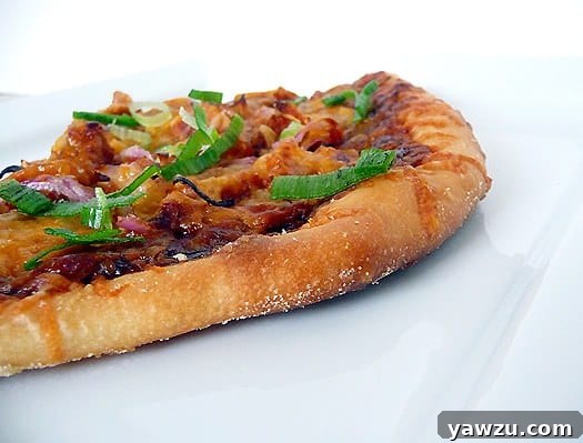 A mouth-watering BBQ Chicken Pizza, generously topped with shredded chicken, tangy barbecue sauce, sliced red onion, and gooey melted cheese.