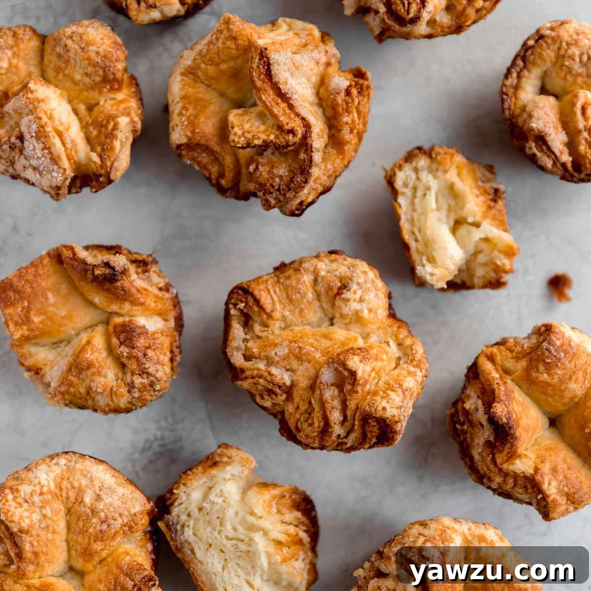 Freshly baked Kouign-Amann pastries, glistening with caramelized sugar, arranged on a cooling rack.