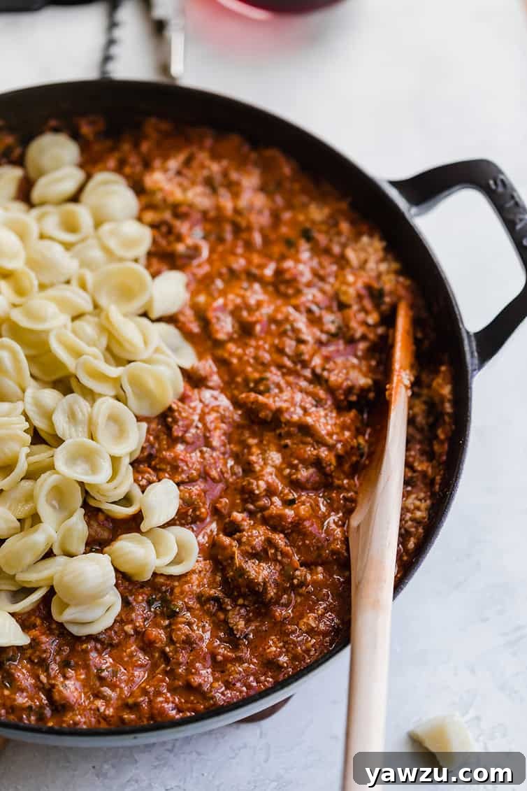 Orecchiette pasta tossed and mixed into a pan of rich bolognese sauce.