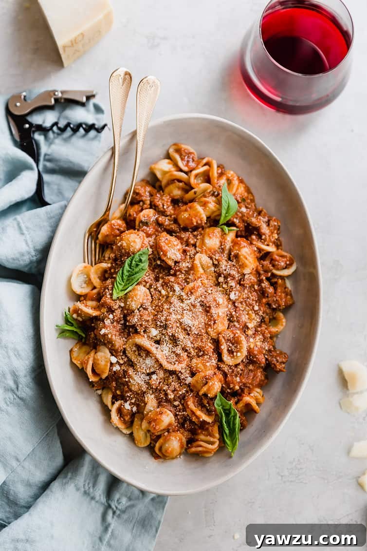An overhead shot of a large serving dish brimming with pasta and rich bolognese sauce, ready to be served.