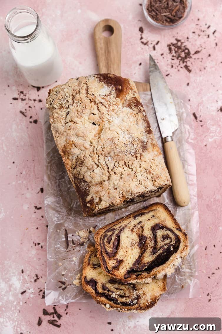 An overhead shot of a freshly baked chocolate babka loaf with two slices cut from it, revealing the intricate chocolate swirls within the tender bread.