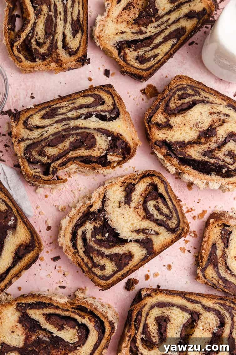 Several slices of chocolate babka, showing the distinct chocolate swirls, arranged appealingly on a wooden serving board.