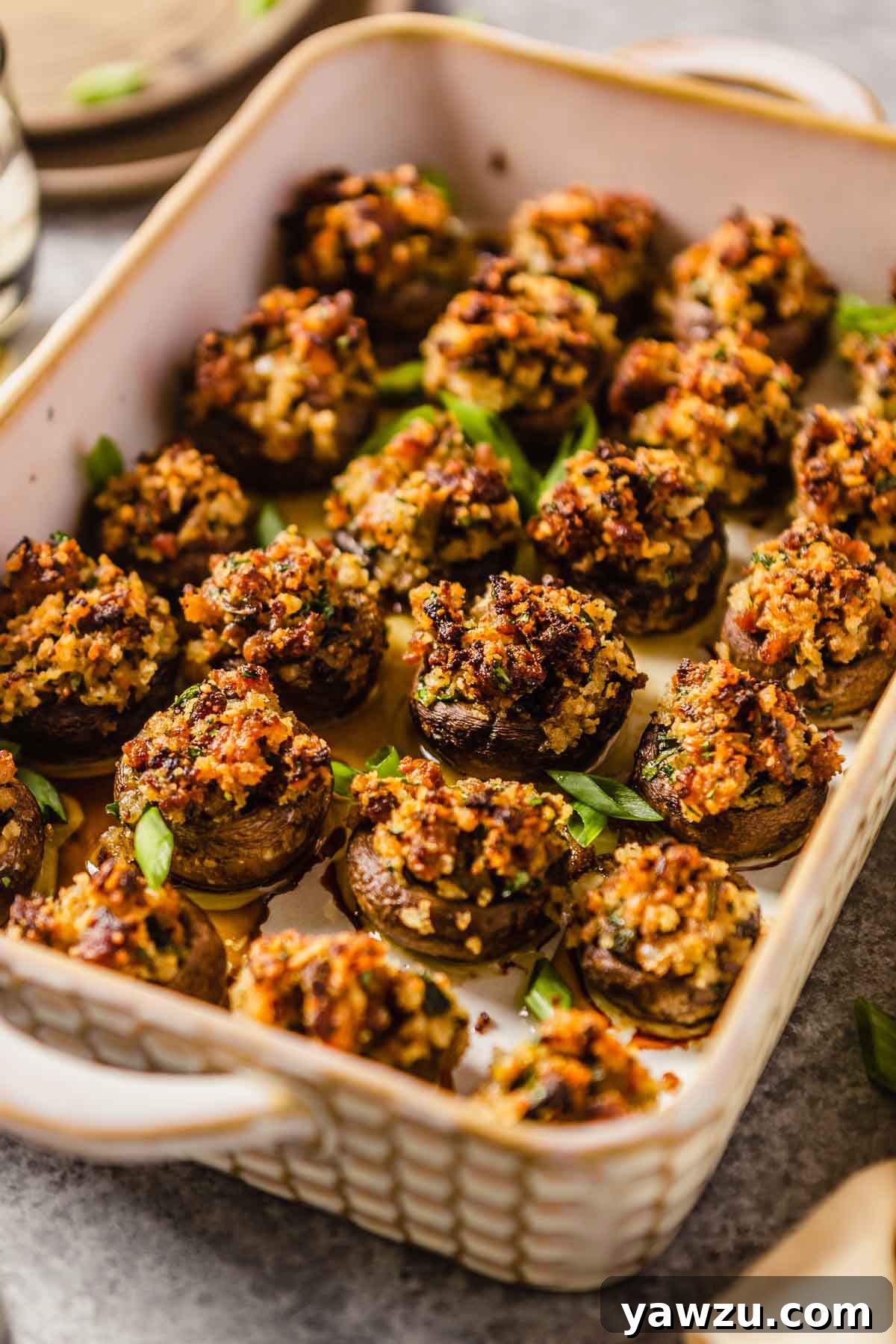 A rectangular baking dish filled with golden-brown sausage stuffed mushrooms, ready to be served as an appetizer.