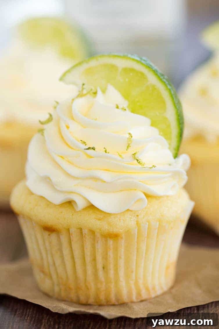 A beautifully decorated Margarita Cupcake, topped with a swirl of buttercream, lime zest, and a lime wedge garnish.