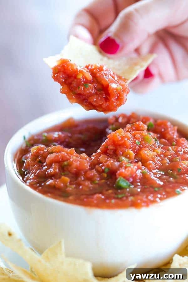 A bowl of Homemade Restaurant Style Salsa, garnished with cilantro, ready for dipping with tortilla chips.