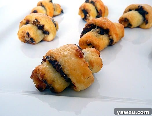 Golden brown rugelach cookies on a white plate, ready to be served, inviting a taste of traditional sweetness.
