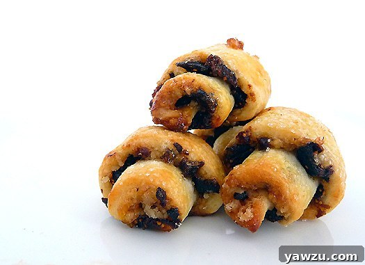 Three perfectly baked rugelach cookies, showcasing their golden crust, crescent shape, and inviting texture.