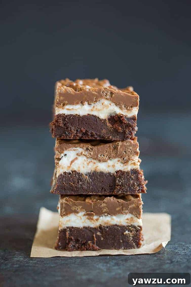 A stack of Marshmallow Crunch Brownie Bars, showing the fudgy brownie, marshmallow layer, and crisp chocolate peanut butter topping.