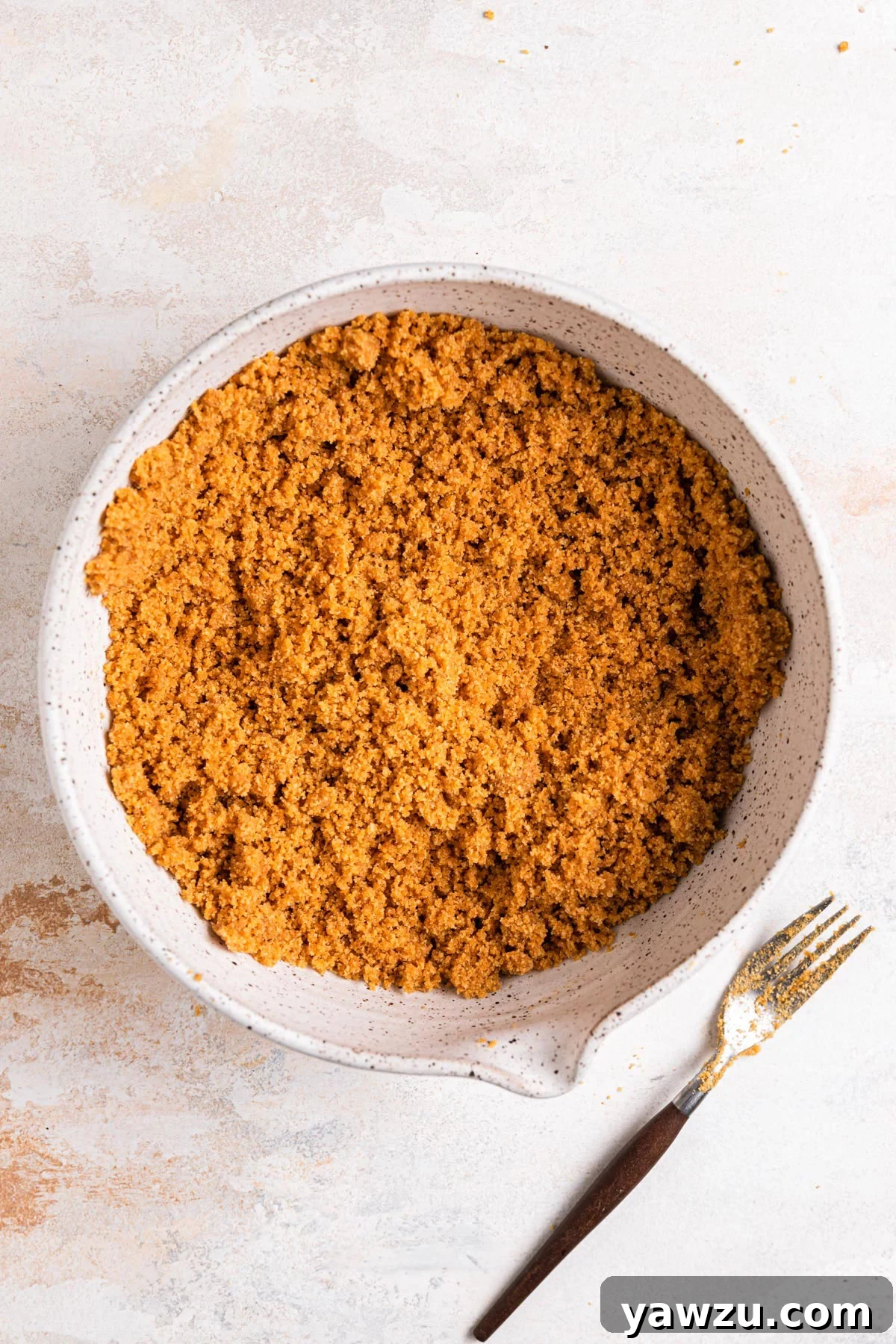 Graham cracker crust stirred together in a mixing bowl.