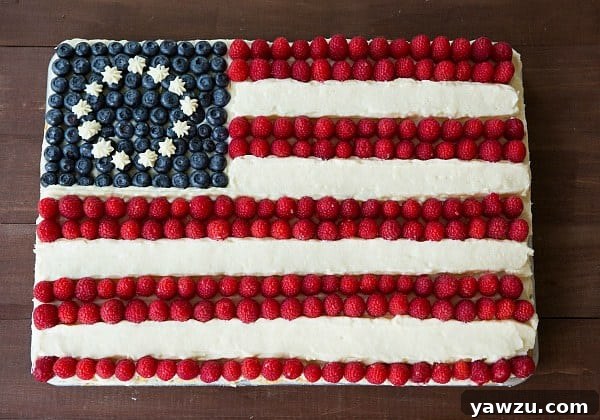 A classic, entirely homemade Flag Cake with luscious cream cheese frosting, decorated with fresh berries, featured on Brown Eyed Baker.
