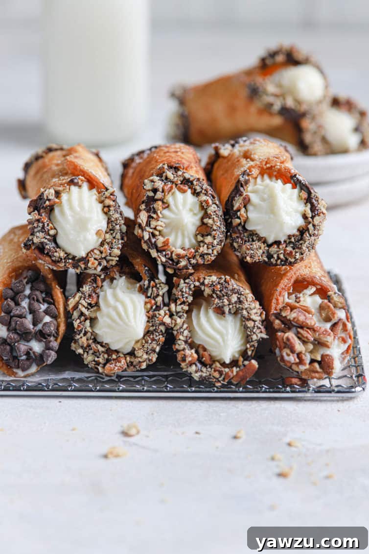 A stack of homemade cannoli on a wire rack with parchment paper and a bottle of milk in the back.