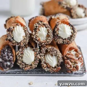 Two rows of homemade cannoli stacked on each other on top of a cooling rack.