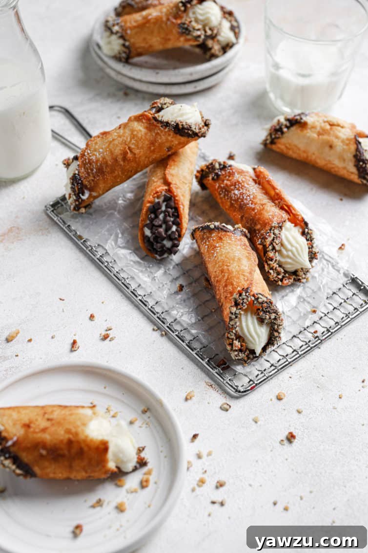 Four cannoli on a wire rack with another cannoli on a white plate in the front left.