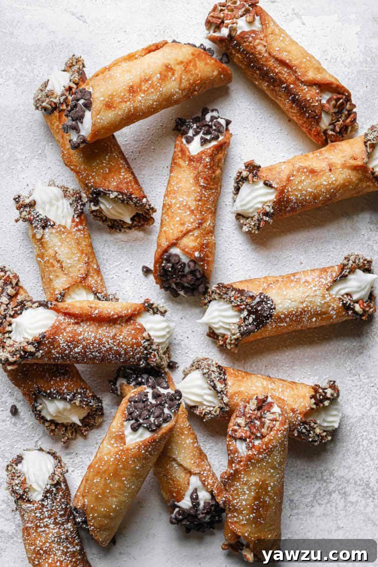 A counter with various cannolis dipped in nuts or chocolate.