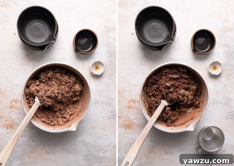 A rubber spatula gently folding dry ingredients into a rich, dark chocolate batter in a large mixing bowl, ensuring careful incorporation for moist chocolate muffins.