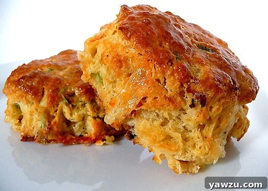 Two golden-brown Quiche Lorraine scones resting on a pristine white plate, promising a delightful savory experience.