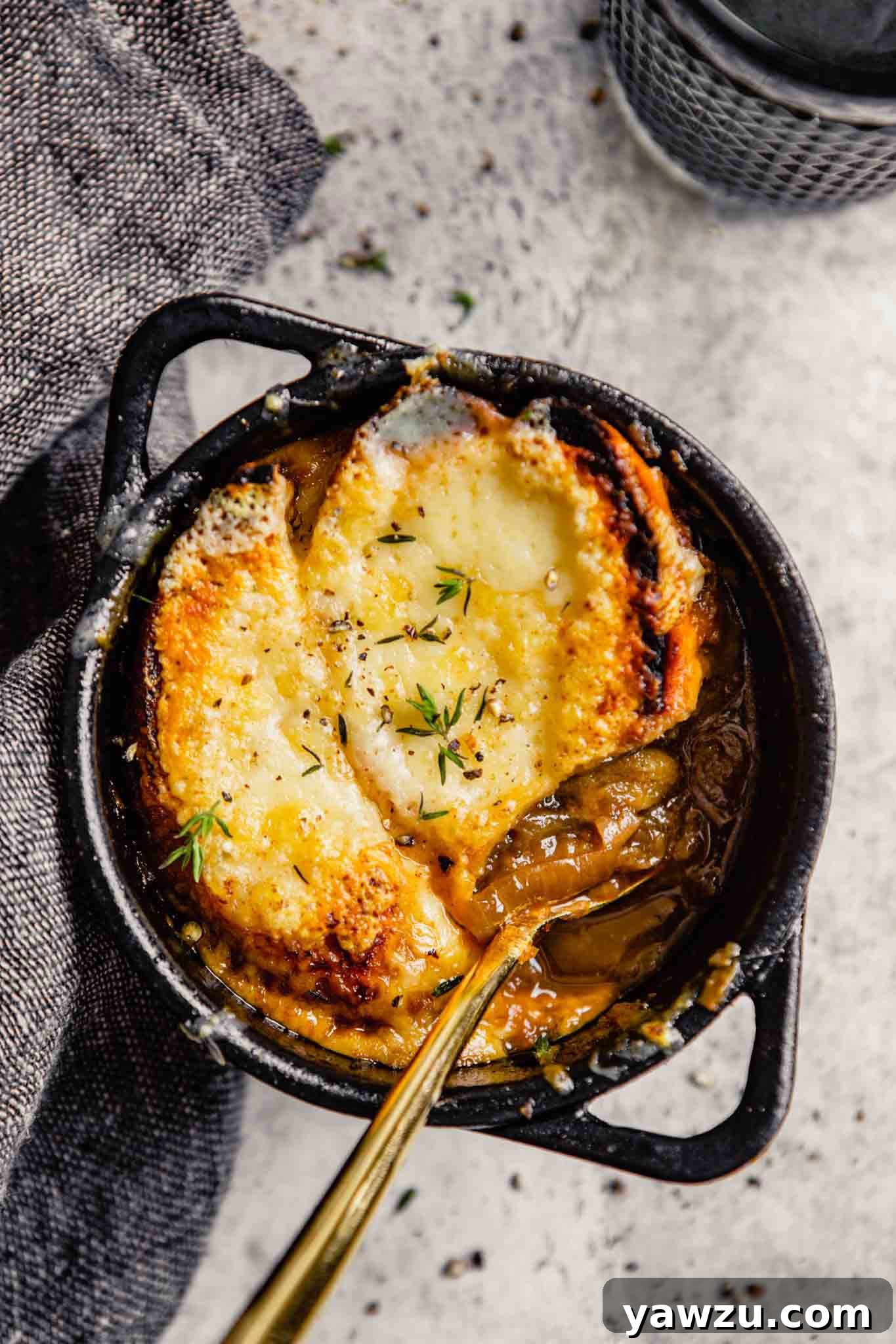 A bowl of French Onion Soup with a spoon inside.