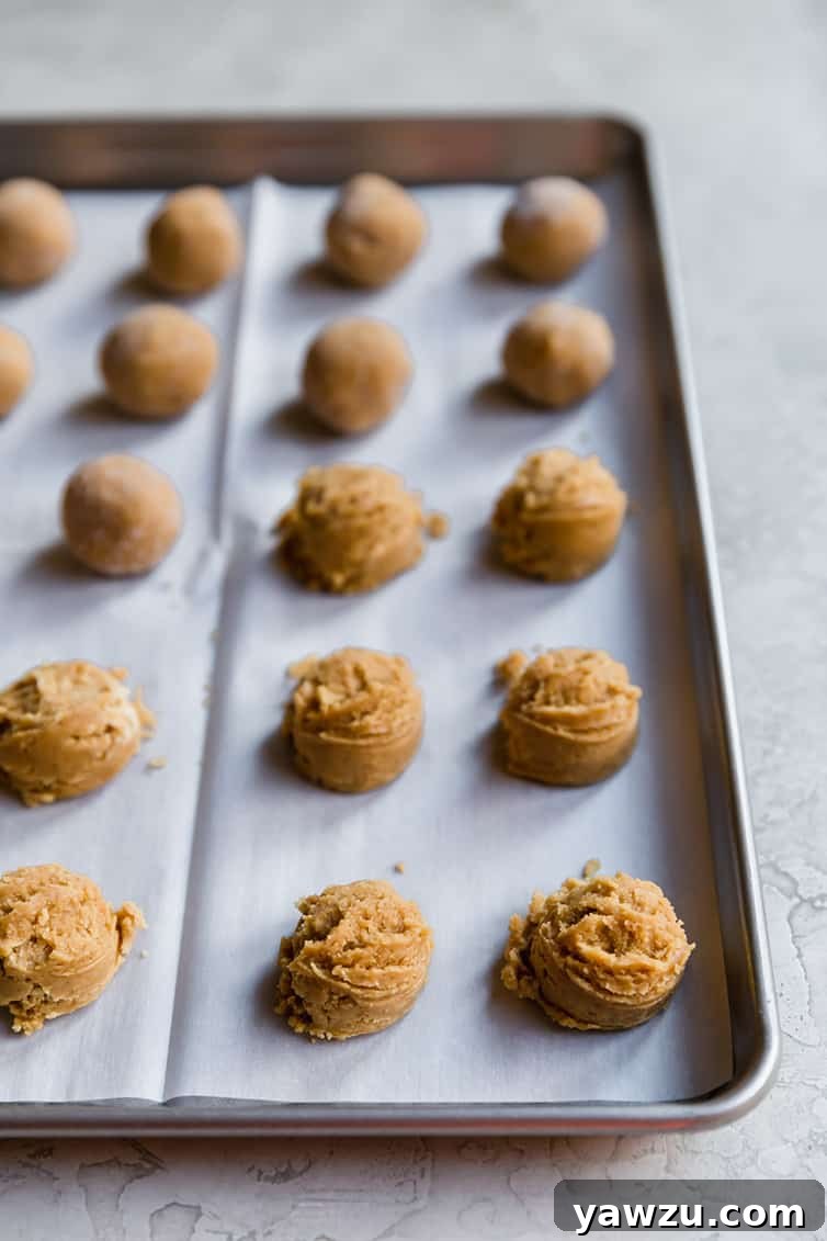 A baking sheet filled with perfectly rolled peanut butter cookie dough balls, ready for the oven.