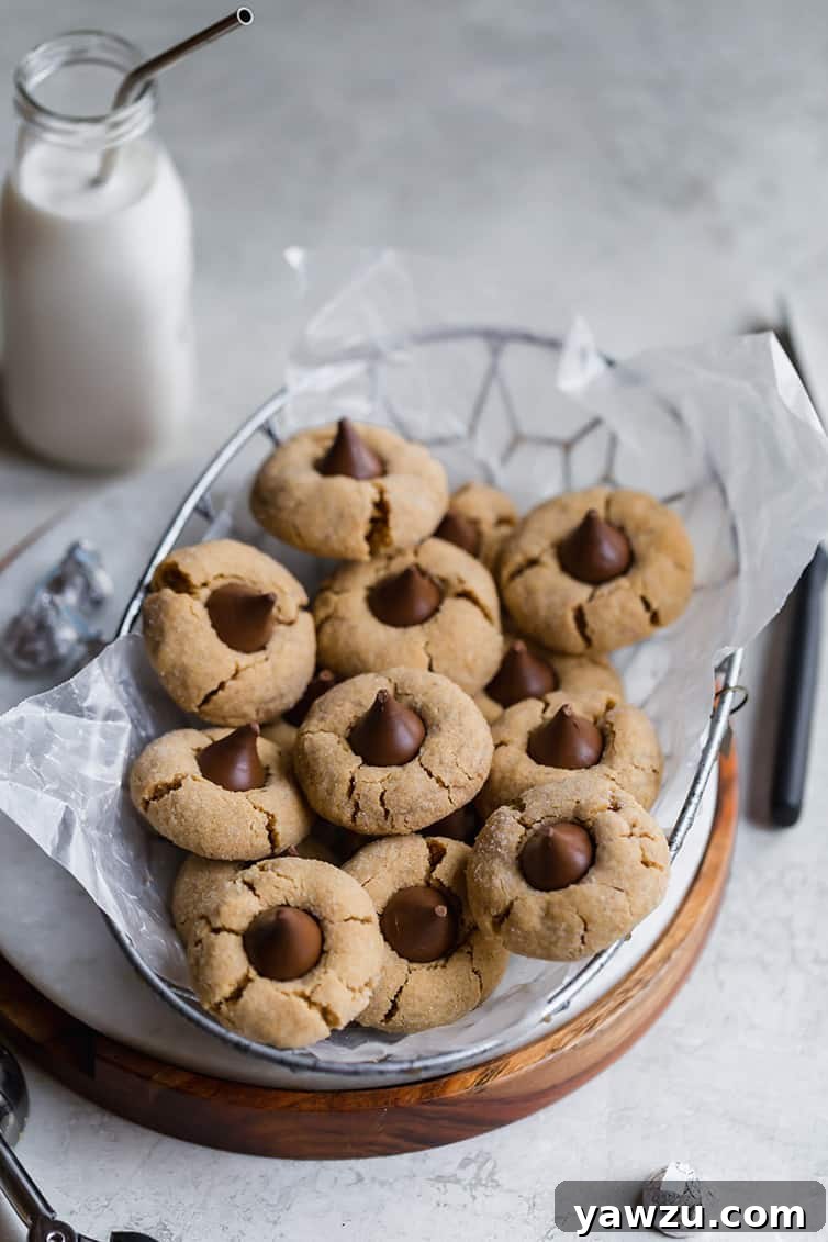 A charming basket filled with freshly baked Peanut Butter Blossoms, with a refreshing glass of milk beside it.