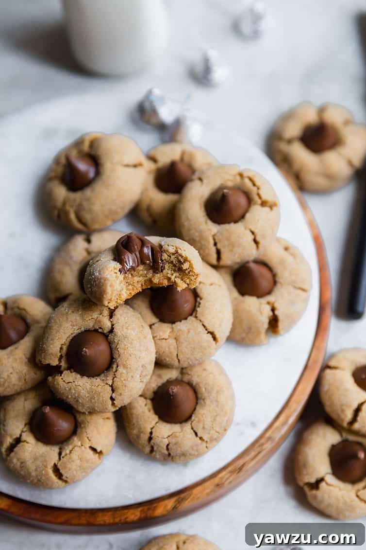 A marble serving tray featuring several Peanut Butter Blossoms, one of which has been bitten in half to reveal its soft interior.