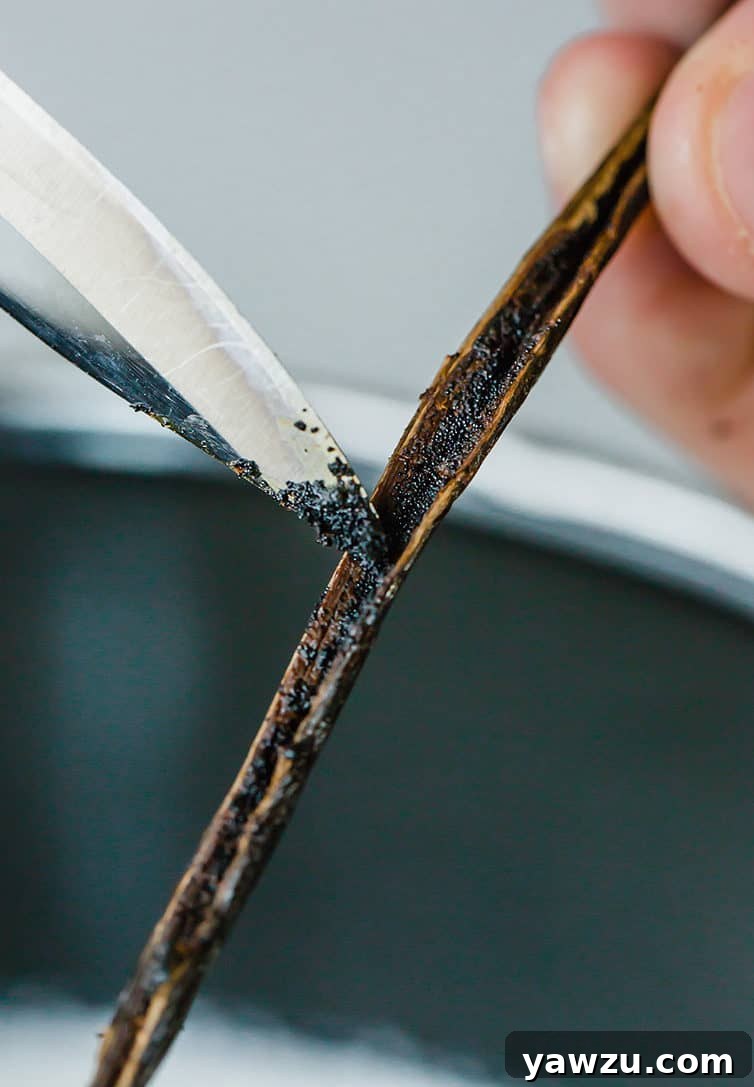 Scraping vanilla bean seeds with a paring knife to flavor the cream.