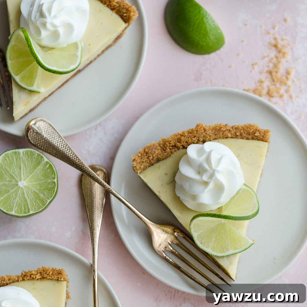 Overhead view of individual slices of traditional Key Lime Pie, each topped with a swirl of fresh whipped cream, on white plates.