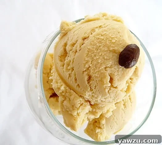 Scoops of rich espresso ice cream in a clear glass bowl, topped with a few whole coffee beans.