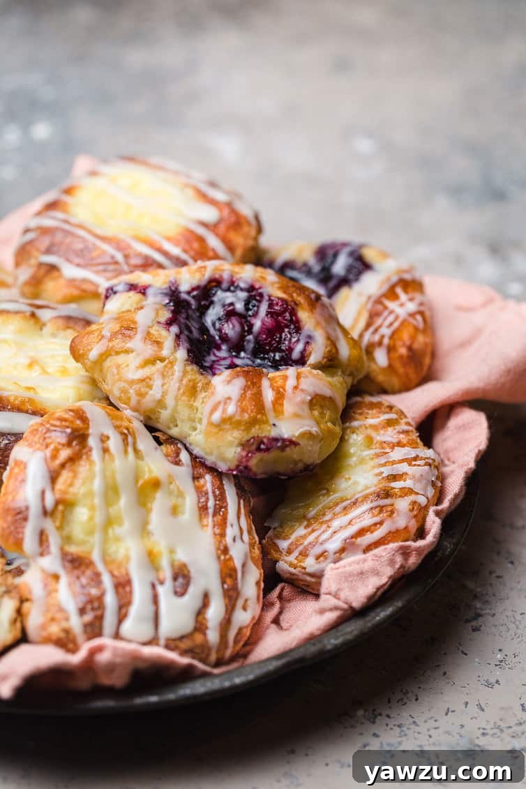 A plate of perfectly baked cheese and fruit Danish pastries, glistening with a sweet glaze.