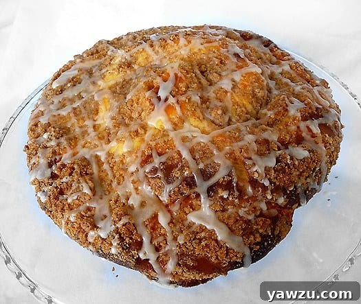 Overhead view of coffee cake with sweet cheese filling and vanilla icing on a glass cake stand.