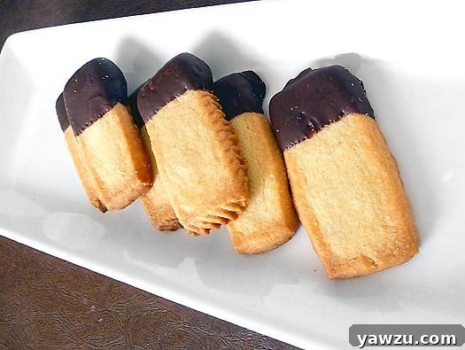 Delectable shortbread fingers, each end generously dipped in dark chocolate, beautifully presented on a pristine white serving tray.