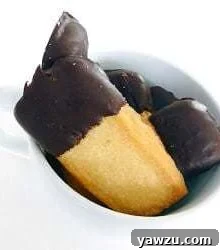 Shortbread cookies with half of each cookie dipped in chocolate in a white mug.