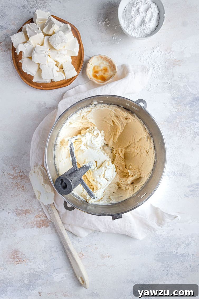 Cream cheese frosting being expertly mixed to perfection in a stand mixer, showcasing its developing smooth texture.