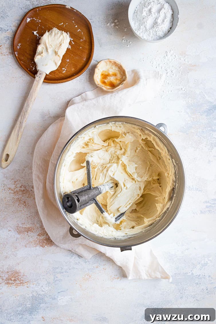 Close-up of perfectly whipped cream cheese frosting in a bowl, showing its incredibly smooth and creamy texture.
