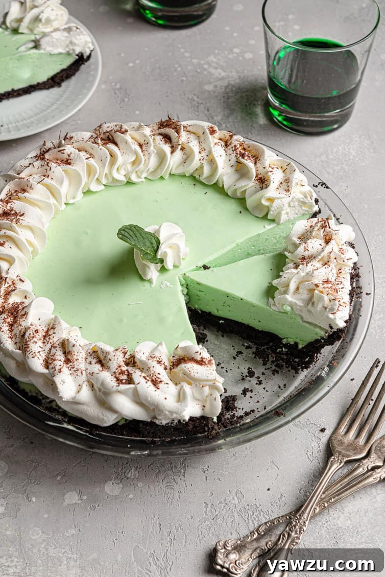A vibrant green grasshopper pie with a perfect slice removed, showcasing its creamy texture and chocolate crust.