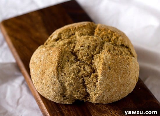A rustic loaf of Irish Brown Bread, with a hearty, wholesome texture and rich color, sliced and ready to be enjoyed with butter.
