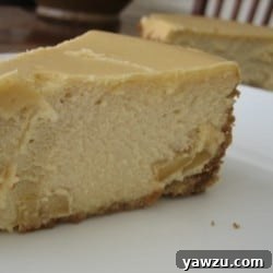 Slice of brown sugar apple cheesecake on a white plate, ready to be served.