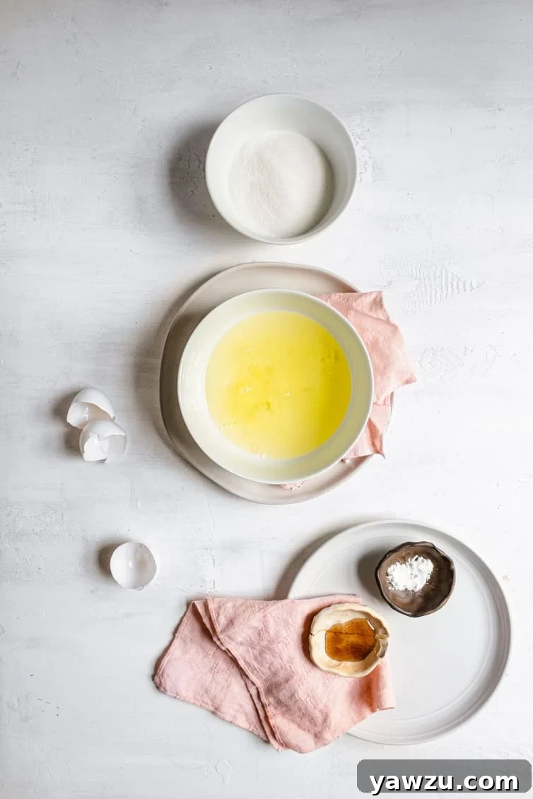 Ingredients for meringue laid out in bowls: egg whites, granulated sugar, cream of tartar, vanilla extract, and salt.