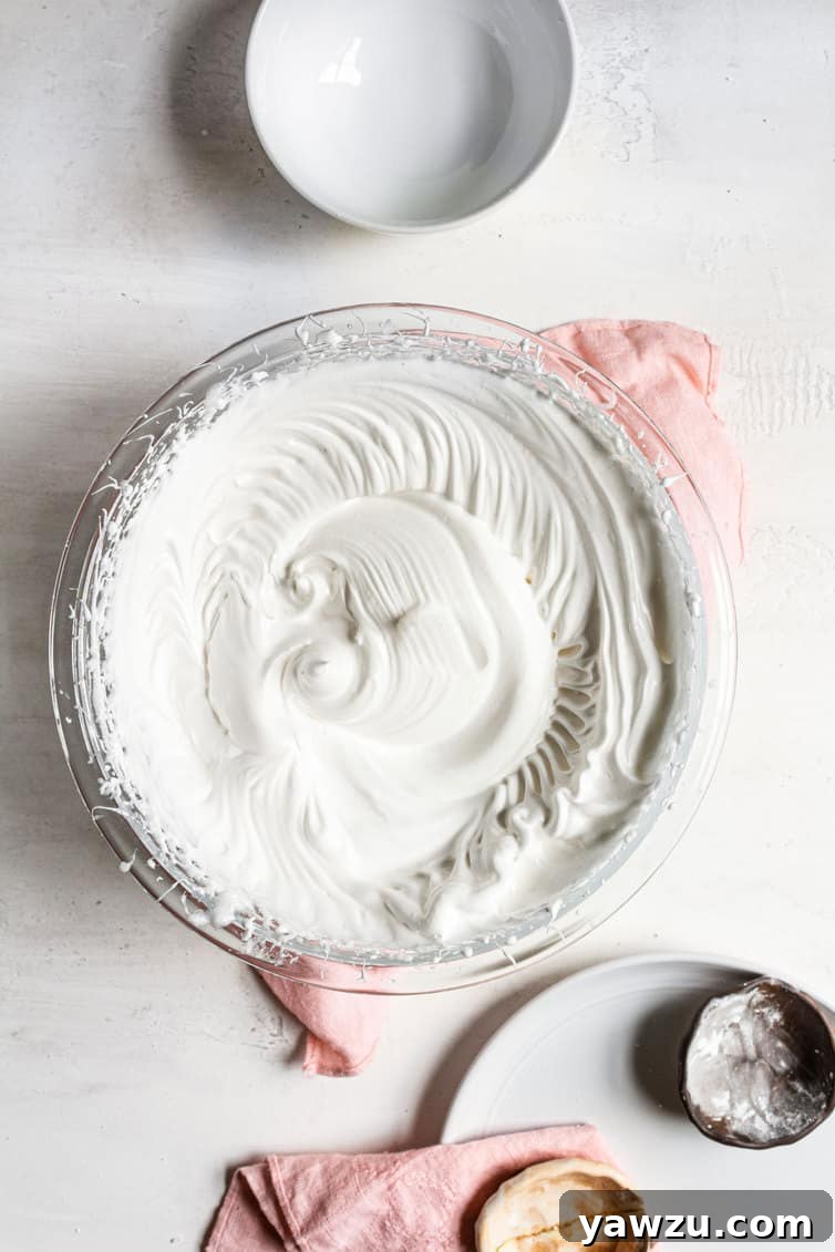Perfectly whipped, glossy meringue filling a large mixing bowl.