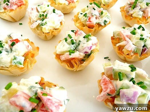 Cucumber tomato bruschetta appetizer pastry cups on a white plate.