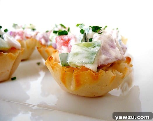 Cucumber tomato bruschetta appetizer pastry cups on a white plate.
