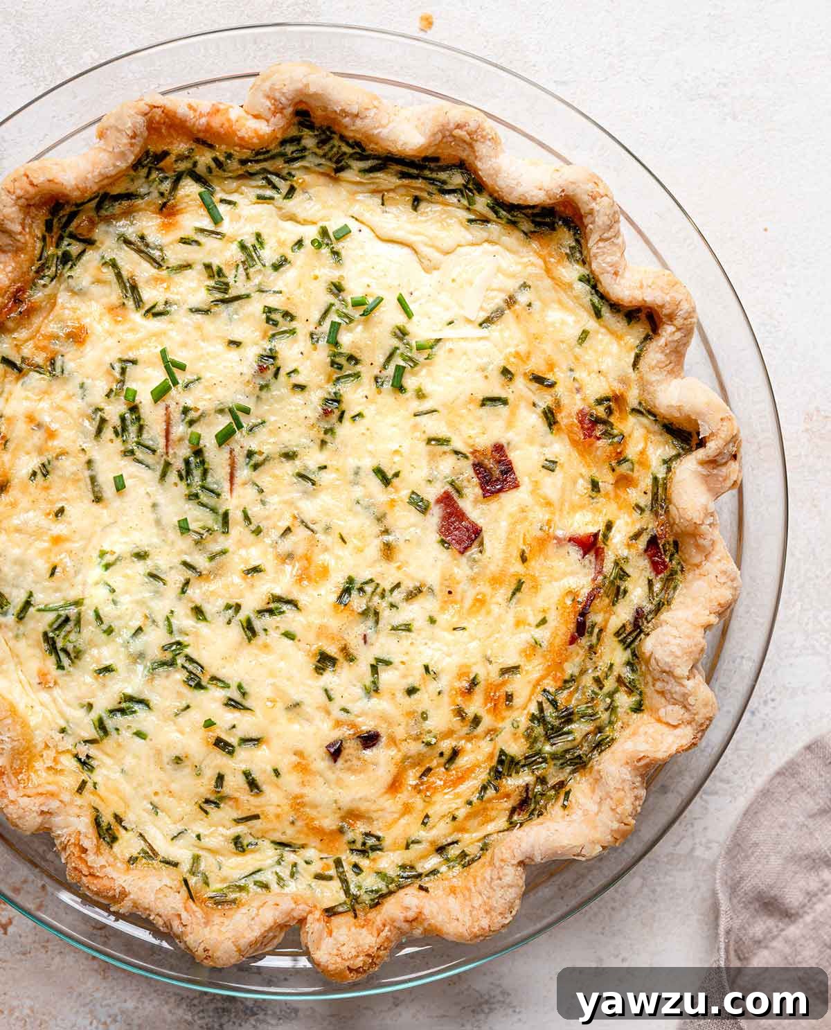 Overview photo of baked quiche Lorraine in glass pie plate.
