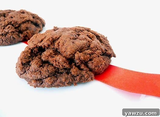 Two irresistibly thick and chewy triple chocolate cookies on a white plate, showcasing their rich color and decadent texture.